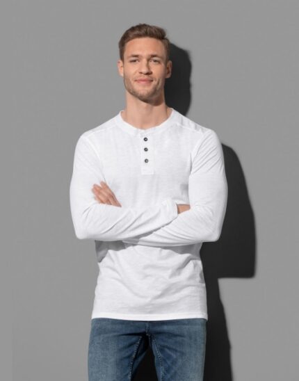 Ένας άντρας που φοράει μια μακρυμάνικη λευκή μπλούζα με τρία κουμπιά και τζιν
