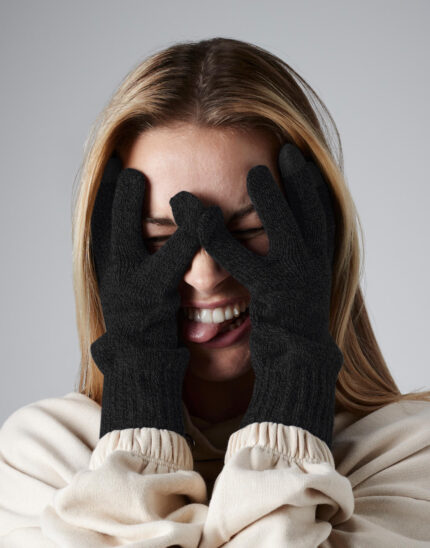 γυναίκα που φοράει unisex γάντια ενηλίκων με ειδικό πλέξιμο στις άκρες για τον χειρισμό ηλεκτρονικών συσκευών σε χρώμα μαύρο